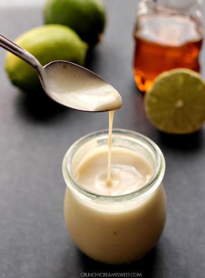 Honey Citrus Dressing in a glass jar with a spoon.