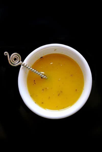 Lemon Herb Vinaigrette in a cup with a stir stick.